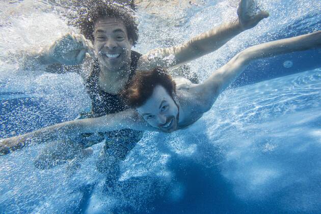 Two men swimming under water in a swimming pool.  MintxImages JamelxToppin