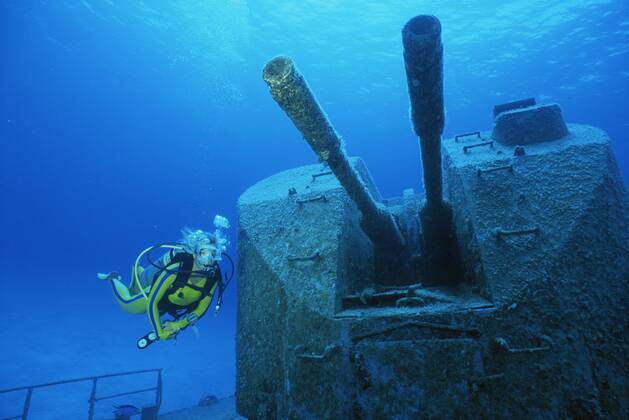 Diver examines cannons on wreck of Russian missile frigate, Destroyer 356, renamed MV Capt Keith Tibbets, Cayman Islands, Caribbean  1150731 DougxPerrine