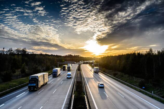 Autos und Lkw fahren auf der A2 bei Helmstedt (Niedersachsen) im Sonnenuntergang.