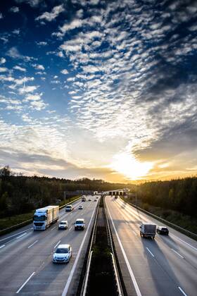 Autos und Lkw fahren auf der A2 bei Helmstedt (Niedersachsen) im Sonnenuntergang.