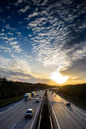 Autos und Lkw fahren auf der A2 bei Helmstedt (Niedersachsen) im Sonnenuntergang.
