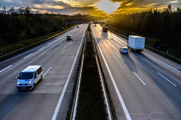 Autos und Lkw fahren auf der A2 bei Helmstedt (Niedersachsen) im Sonnenuntergang.
