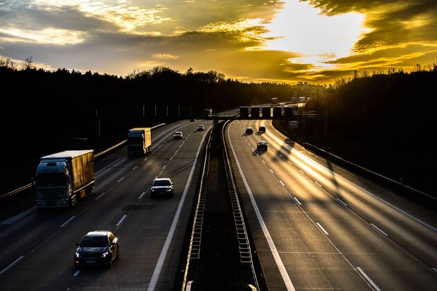 Autos und Lkw fahren auf der A2 bei Helmstedt (Niedersachsen) im Sonnenuntergang.