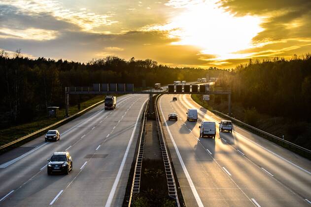 Autos und Lkw fahren auf der A2 bei Helmstedt (Niedersachsen) im Sonnenuntergang.