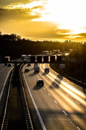 Autos und Lkw fahren auf der A2 bei Helmstedt (Niedersachsen) im Sonnenuntergang.