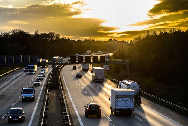 Autos und Lkw fahren auf der A2 bei Helmstedt (Niedersachsen) im Sonnenuntergang.