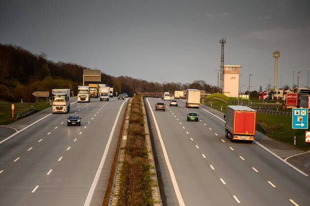 Autos und Lkw fahren auf der A2 bei Helmstedt (Niedersachsen) im Sonnenuntergang.