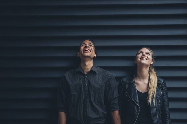 Black dressed young couple standing in front of black facade looking up model released Symbolfoto CHAF001378