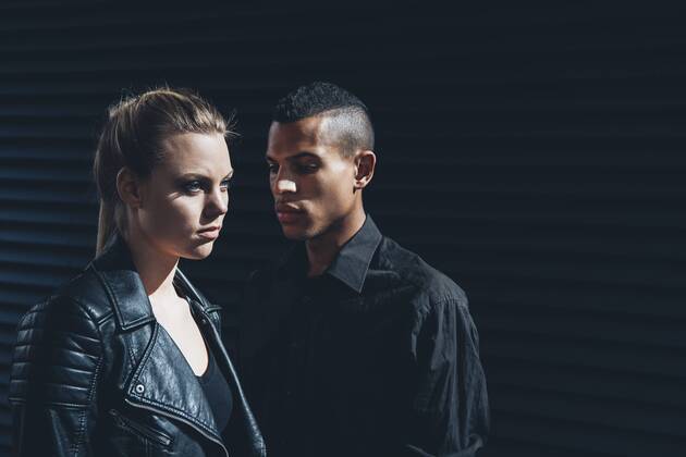 Black dressed young couple standing in front of black facade model released Symbolfoto CHAF001384