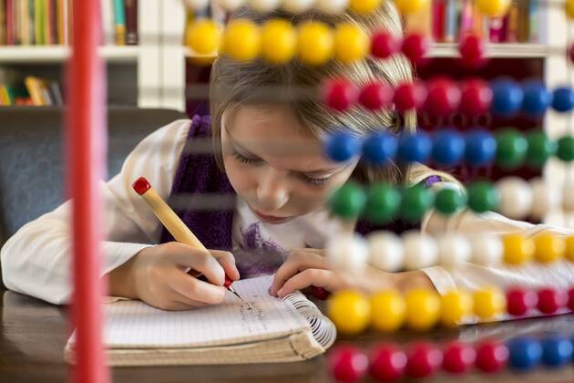 IMAGO Creative: Gesellschaft, Schule, Schulanfang Girl sitting behind abacus doing homework  SARF002176