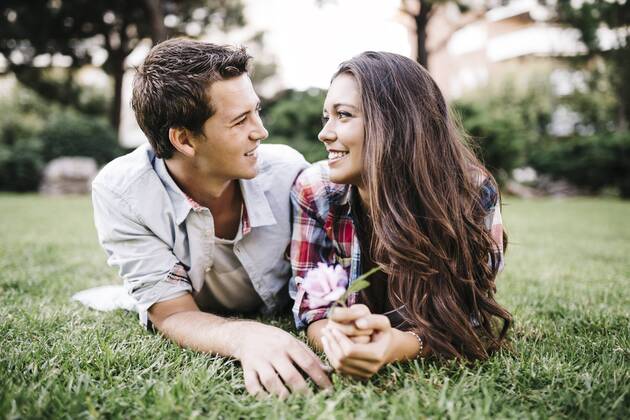 Young couple in love lying on a meadow in a park looking at each other JRFF000109