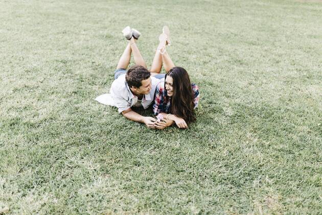 Young couple in love lying on a meadow in a park looking at each other JRFF000112