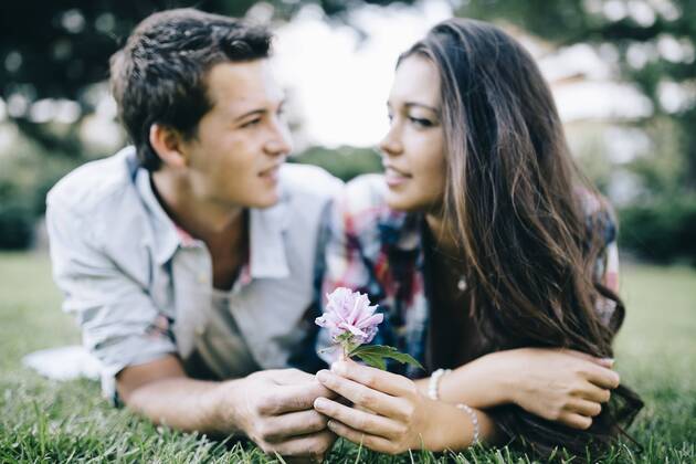 Young couple in love lying on a meadow in a park looking at each other JRFF000131
