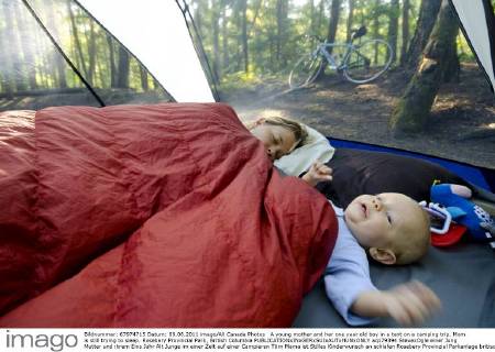 A young mother and her one year old boy in a tent on a camping trip. Mom is still trying to sleep. Rosebery Provincial Park, British Columbia  acp79394 StevexOgle