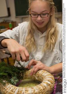 Teenager bindet selber Adventskranz  1077402934