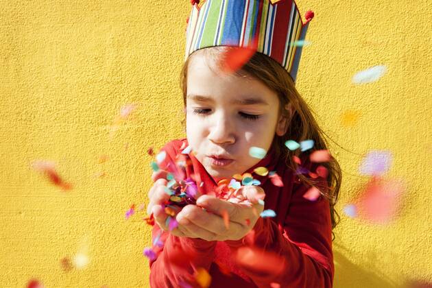 Portrait of little girl wearing paper crown blowing confetti model released Symbolfoto  VABF000211