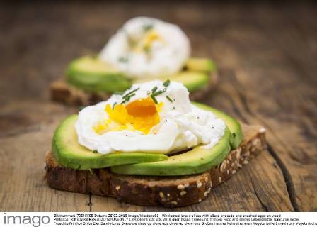 Wholemeal bread slices with sliced avocado and poached eggs on wood  LVF004673