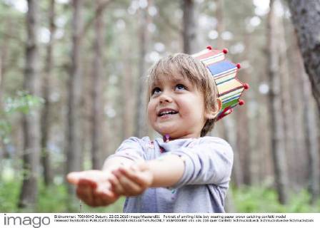 Portrait of smiling little boy wearing paper crown catching confetti model released Symbolfoto  VABF000360