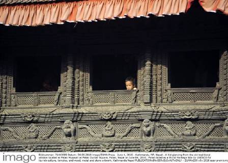 June 4, 2016 - Kathmandu, NP, Nepal - A Kid glancing from the old traditional window located at Patan Museum at Patan Durbar Square, Patan, Nepal on June 04, 2016.. Patan listed as a World Heritage Site by UNESCO for its rich culture, temples, and wood, metal and stone artwork. Kathmandu Nepal  - ZUMAn230