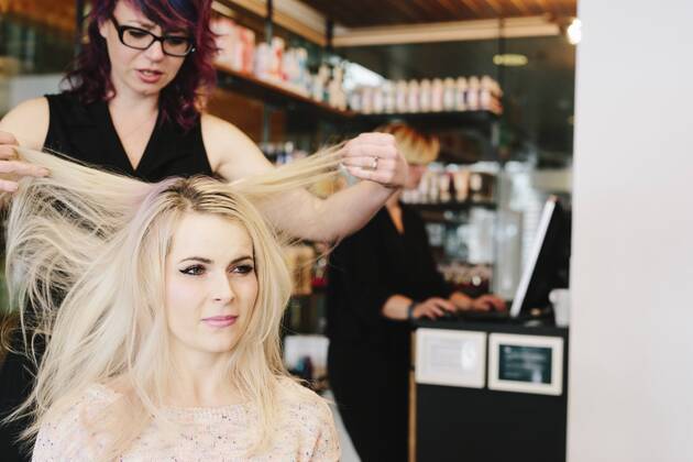 A hair stylist and a client, a young woman with long blonde hair, at a hair salon. A hair stylist and a client, a young woman with long blonde hair, at a hair salon. 21690