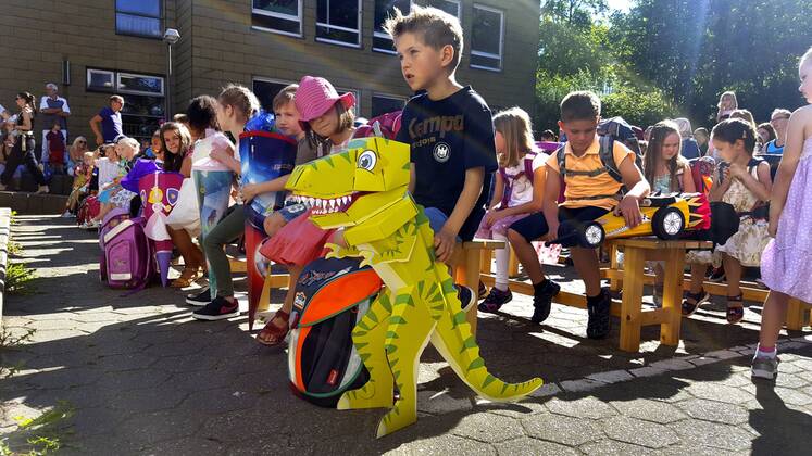 I-Maennchen bei der Einschulung mit Ihren Schultueten auf dem Schulhof, im Vordergrund ein Kind mit Dinosaurier-Schultuete, Deutschland first-grader with their first day at school with school cones on the schoolyard, Germany BLWS435872 Copyright: xblickwinkel fotototox