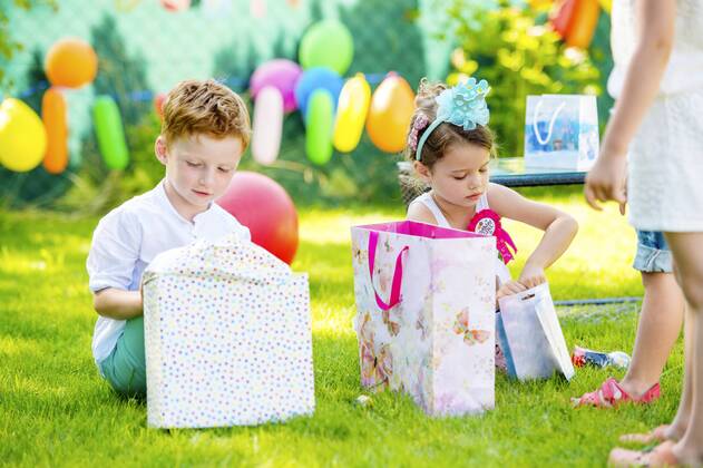 Little boy and girl unpacking birthday presents in the garden model released Symbolfoto  HAPF000740