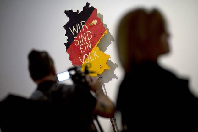 The British View Germany - Memories of a Nation, Exhibition Gropius-Bau DEU, Deutschland, Germany, Berlin, 07.10.2016 Besucher neben dem Schild Wir Sind Das Volk von Eckart Conradt, ein Transparent fuer die Demonstration im Berliner Lustgarten am 09. Dezember 1989, in der Ausstellung Der Britische Blick Deutschland - Erinnerungen einer Nation, The British View German - Memories of a Nation, im Martin-Gropius-Bau in Berlin. Die Ausstellung eroeffnet am 08. Oktober und geht bis 09. Januar und praesentiert ca 200 Objekte welche einen Bezug zu den letzten 600 Jahre Geschichte in Deutschland haben. Sie zeigt Spuren deutscher Identitaet aus britischer Perspektive. Visitor next to a poster We are one People by Eckart Conradt for a protest march in Berlin s Lustgartem on December 9th 1989 in Berlin, on display during his exhibition Der Britische Blick Deutschland - Erinnerungen einer Nation, The