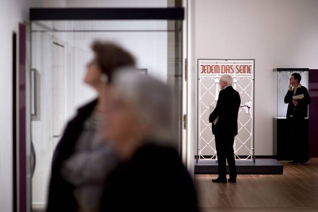 The British View Germany - Memories of a Nation, Exhibition Gropius-Bau DEU, Deutschland, Germany, Berlin, 07.10.2016 Besucher betrachtet das Lagertor des Konzentrationslager KZ Buchenwald mit der Inschrift Jedem das Seine in der Ausstellung Der Britische Blick Deutschland - Erinnerungen einer Nation, The British View German - Memories of a Nation, im Martin-Gropius-Bau in Berlin. Die Ausstellung eroeffnet am 08. Oktober und geht bis 09. Januar und praesentiert ca 200 Objekte welche einen Bezug zu den letzten 600 Jahre Geschichte in Deutschland haben. Sie zeigt Spuren deutscher Identitaet aus britischer Perspektive. Visitor next to a gate from the former Buchenwald concentration camp with the words Jedem das Seine, To Each What He Deserves, on display during his exhibition Der Britische Blick Deutschland - Erinnerungen einer Nation, The British View German - Memories of a Nation, at the