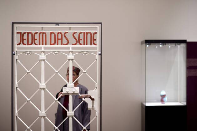 The British View Germany - Memories of a Nation, Exhibition Gropius-Bau DEU, Deutschland, Germany, Berlin, 07.10.2016 Besucher betrachtet das Lagertor des Konzentrationslager KZ Buchenwald mit der Inschrift Jedem das Seine in der Ausstellung Der Britische Blick Deutschland - Erinnerungen einer Nation, The British View German - Memories of a Nation, im Martin-Gropius-Bau in Berlin. Die Ausstellung eroeffnet am 08. Oktober und geht bis 09. Januar und praesentiert ca 200 Objekte welche einen Bezug zu den letzten 600 Jahre Geschichte in Deutschland haben. Sie zeigt Spuren deutscher Identitaet aus britischer Perspektive. Visitor next to a gate from the former Buchenwald concentration camp with the words Jedem das Seine, To Each What He Deserves, on display during his exhibition Der Britische Blick Deutschland - Erinnerungen einer Nation, The British View German - Memories of a Nation, at the