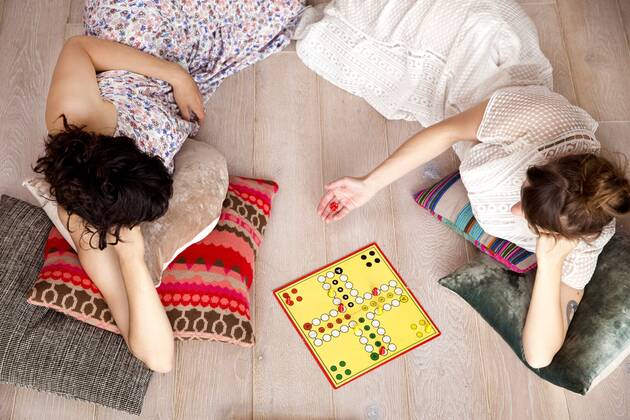 Top view of two best friends lying on the floor at home playing ludo model released Symbolfoto property released  TSFF000111