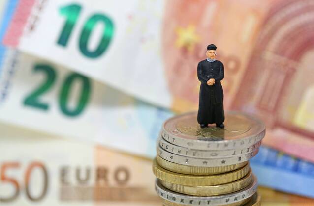 Nuernberg Symbolfoto, Themenbild Kirchensteuer. Geistlicher mit Soutane steht auf Euro Muenzen. Im Hintergrund verschiedene Euro Banknoten. Copyright: xWuestx Eibner-Pressefotox EP_fwt