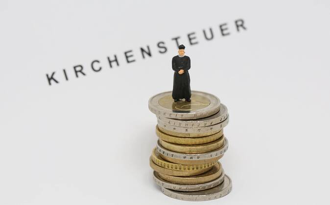 Nuernberg Symbolfoto, Themenbild Kirchensteuer. Geistlicher mit Soutane steht auf Euro Muenzen. Im Hintergrund Schriftzug Kirchensteuer. Copyright: xWuestx Eibner-Pressefotox EP_fwt
