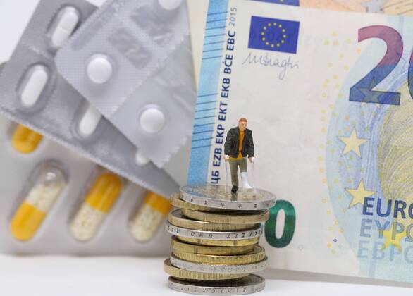 Nuernberg Symbolfoto, Themenbild Krankenversicherung, Krankenkassenbeitrag, Arzneimittelkosten. Mann mit Gips und Gehhilfe steht auf Euro Muenzen. Im Hintergrund verschiedene Arzneimittel und Euro Banknoten. Copyright: xWuestx Eibner-Pressefotox EP_fwt