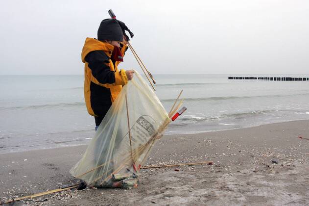 01.01.2006, Zingst, Mecklenburg-Vorpommern, DEU - Ein Kind sammelt abgebrannte Silvesterraketen am Strand ein. (1. Januar, Erster, Jahresanfang, Jahresbeginn, Jahreswechsel, Januar, Neujahr, Rakete, Raketen, Silvester, Silvesterrakete, Silvesterraketen, Muell, Abfall, Unrat, Muellsack, sammeln, einsammeln, Oekologie, oekologisch, Rest, Reste, Ueberreste, Ueberbleibsel, Umwelt, Umweltschutz, Umweltbewusstsein, umweltbewusst, Muelltuete, Strand, Meer, Wasser, Winter, abgebrannt, abgefeuert, Mensch, Kind, Kindheit, Gesellschaft, Lebenswelt, Lebenswelten, Ostsee, Zingst, Darss, Aussenaufnahme, digital, QF, gefährlich, Müll, Müllsack, Ökologie, ökologisch, Mülltüte, Überbleibsel, Überreste) 00S060101D001.JPG MODEL RELEASE: YES MR:Y