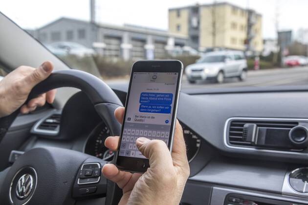 Mann, Autofahrer, benutzt ein Handy, während der Fahrt, SMS schreiben,