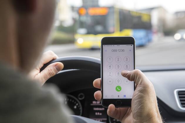 Mann, Autofahrer, benutzt ein Handy, während der Fahrt, wählt Telefonnummer, ohne Freisprecheinrichtung,