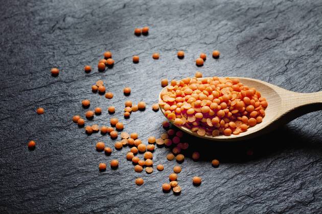 Wooden spoon of red lentils on slate CSF28019