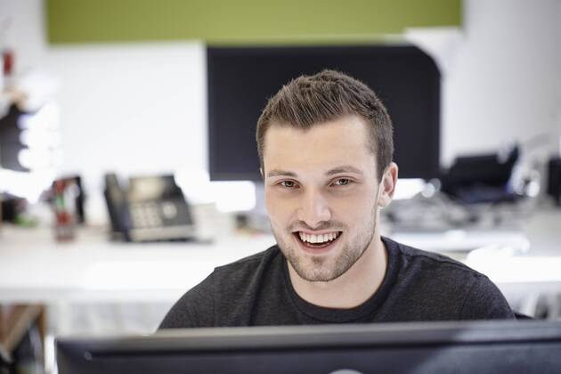 Young man working in office, looking at camera model released Symbolfoto property released RHF01904