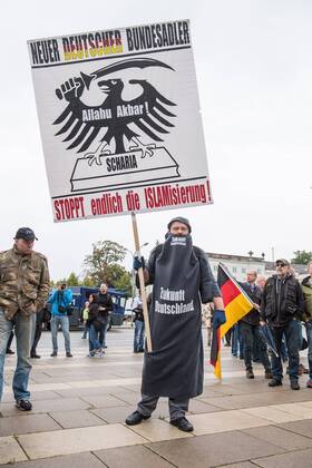 Politik Potsdam AfD-Kundgebung AfD-Kundgebung in Potsdam. Ca. 70 AfD-Anhaenger kamen am Samstag den 9. September 2017 zu einer Wahlveranstaltung der rechtsnationalistischen Alternative fuer Deutschland , AfD. Unter den Teilnehmern waren u.a. Neonazis die Patrioten Cottbus oder die sog. Schwarze Sonne , ein Zeichen der SS auf ihren Jacken trugen. Offiziell hatte die AfD die Kundgebung als Gruendung einer rechten Gewerkschaft namens Alternativer Arbeitnehmerverband Mitteldeutschland (Alarm) in Brandenburg deklariert. 500 Menschen protestierten friedlich gegen die Veranstaltung. Im Bild: Ein Kundgebungsteilnehmer hat sich mit einer selbstgebastelten Burka vermummt um gegen den Islam zu protestieren. 9.9.2017, Potsdam