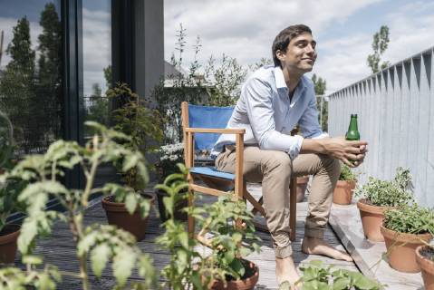 Smiling man with bottle relaxing on balcony model released Symbolfoto property released  JOSF01595