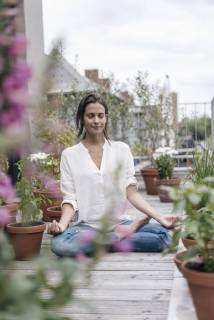 Woman sitting on balcony practicing yoga model released Symbolfoto property released  JOSF01641
