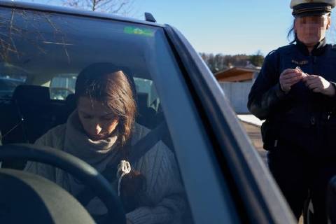 Junge Frau mit Handy am Steuer eines PKW (gestellte Szene) bei einer Polizeikontrolle mit Alkoholkontrolle, Promille, Polizistin, in Marktoberdorf, Bayern, Deutschland am 07.12.2017 FRAU AM STEUER MODEL RELEASED