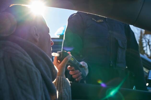Junge Frau mit Handy am Steuer eines PKW (gestellte Szene) bei einer Polizeikontrolle mit Alkoholkontrolle, Promille, Polizistin, in Marktoberdorf, Bayern, Deutschland am 07.12.2017 FRAU AM STEUER MODEL RELEASED