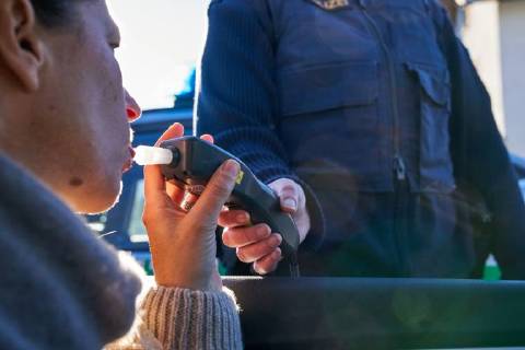 Junge Frau mit Handy am Steuer eines PKW (gestellte Szene) bei einer Polizeikontrolle mit Alkoholkontrolle, Promille, Polizistin, in Marktoberdorf, Bayern, Deutschland am 07.12.2017 FRAU AM STEUER MODEL RELEASED