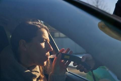 Junge Frau mit Handy am Steuer eines PKW (gestellte Szene) bei einer Polizeikontrolle mit Alkoholkontrolle, Promille, Polizistin, in Marktoberdorf, Bayern, Deutschland am 07.12.2017 FRAU AM STEUER MODEL RELEASED