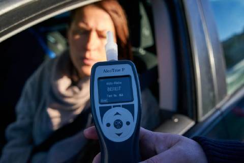 Junge Frau mit Handy am Steuer eines PKW (gestellte Szene) bei einer Polizeikontrolle mit Alkoholkontrolle, Promille, Polizistin, in Marktoberdorf, Bayern, Deutschland am 07.12.2017 FRAU AM STEUER MODEL RELEASED