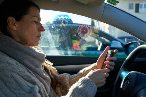 Junge Frau mit Handy am Steuer eines PKW (gestellte Szene) bei einer Polizeikontrolle in Marktoberdorf, Bayern, Deutschland am 07.12.2017 FRAU AM STEUER MODEL RELEASED