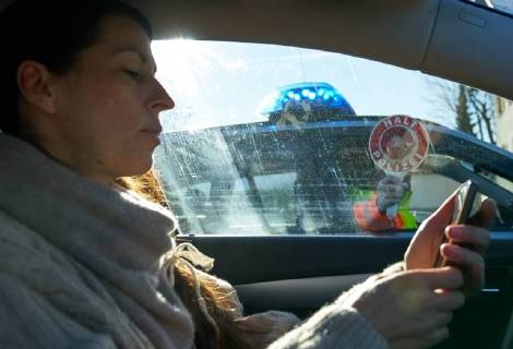 Junge Frau mit Handy am Steuer eines PKW (gestellte Szene) bei einer Polizeikontrolle in Marktoberdorf, Bayern, Deutschland am 07.12.2017 FRAU AM STEUER MODEL RELEASED