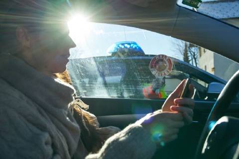 Junge Frau mit Handy am Steuer eines PKW (gestellte Szene) bei einer Polizeikontrolle in Marktoberdorf, Bayern, Deutschland am 07.12.2017 FRAU AM STEUER MODEL RELEASED