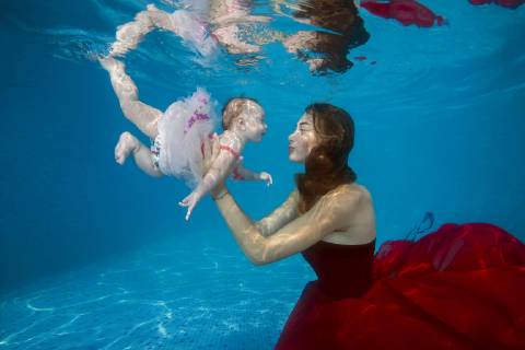 Schöne junge Frau in rotem Kleid mit Baby posiert unter Wasser im Pool, Ukraine, Europa Copyright: imageBROKER/AndreyxNekrasov ibxaaa04630635.jpg